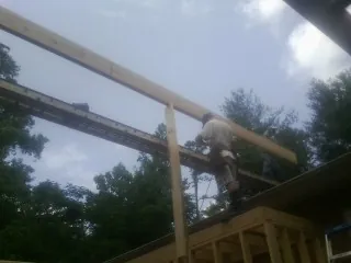 Carpenter setting a ridge beam over a new addition frame — Ice Dam Removal by Roofing Brothers in Albin