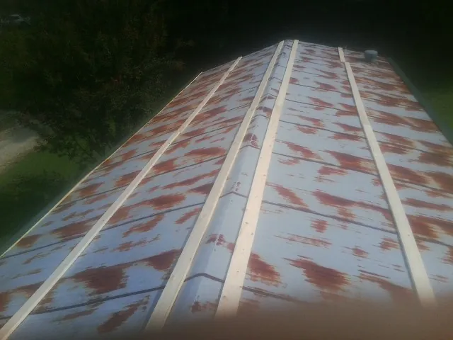 Rusted metal roof panels with new wood purlins before replacement — Storm Damage Roof Repair in Albin by Roofing Brothers