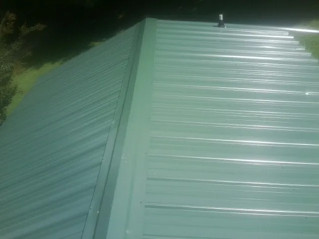 New green metal panels meeting at the ridge of a roof — Flat Roof Repair work by our crew in Albin
