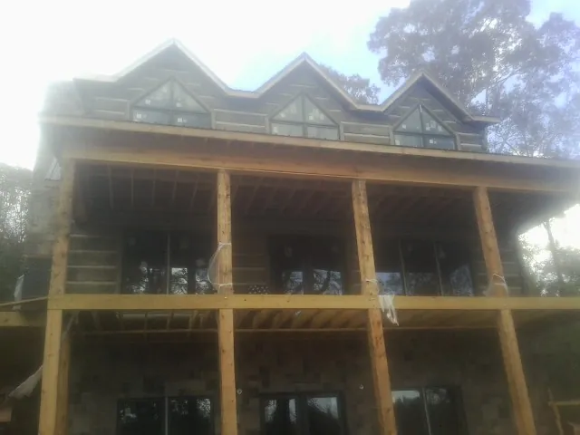 Dormers and porch framing on a large log home under construction — Roof Coating work by our crew in Albin