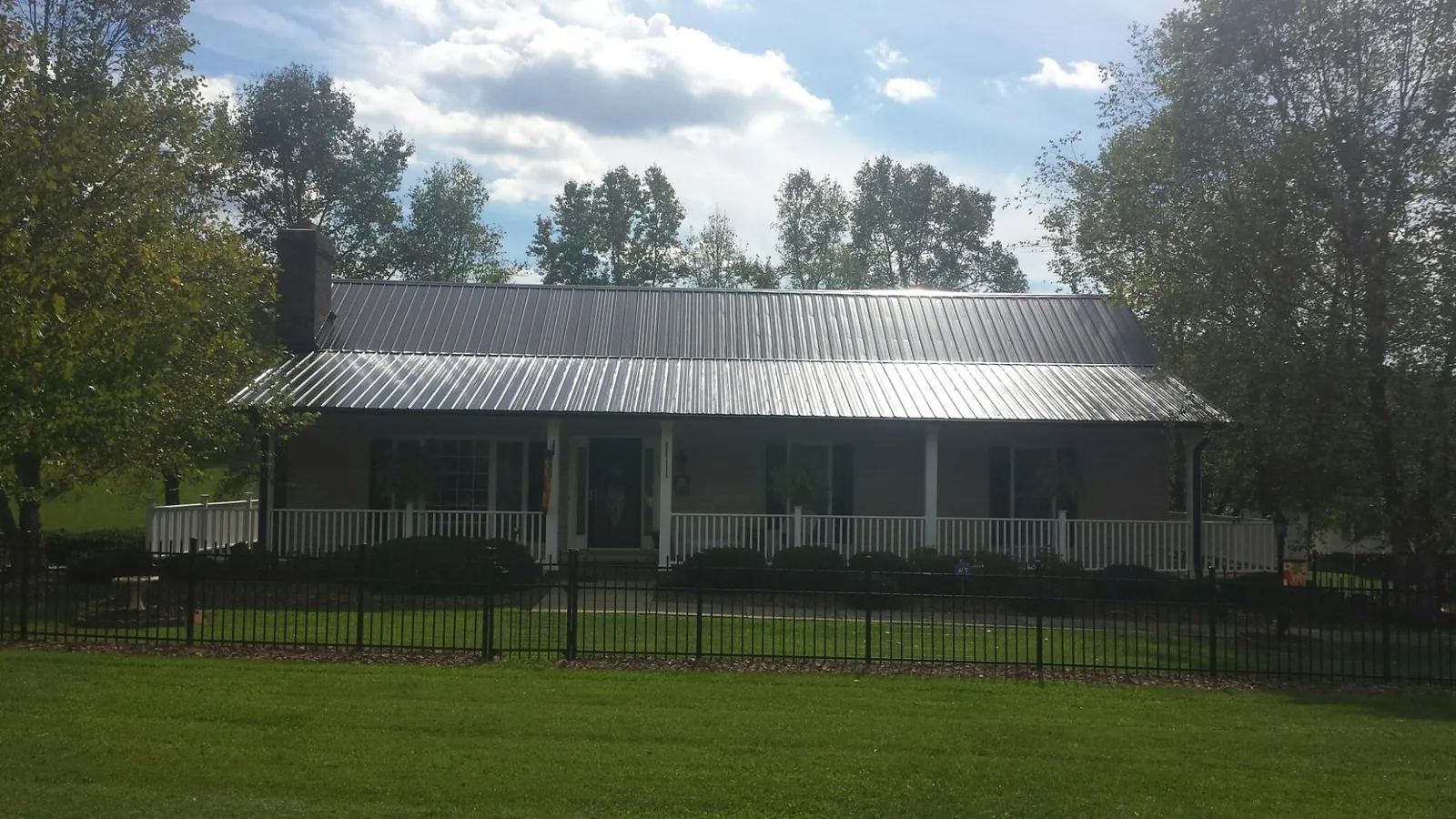 Gray metal roof on a brick ranch with a full width front porch — Gutter Guard Installation work by our crew in Albin