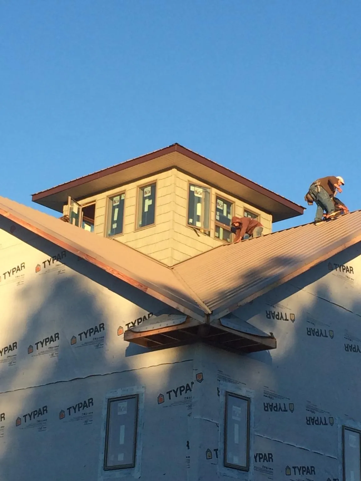 Roofers working around a rooftop cupola on a new metal roof at sunset — Roof Waterproofing in Albin by Roofing Brothers